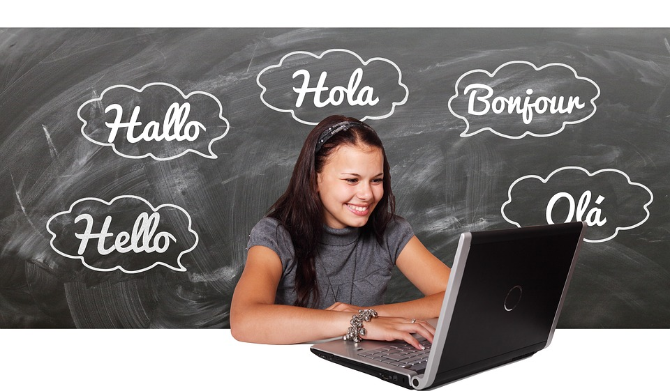 Teenage girl smiling at a computer discovering the benefits of learning a language